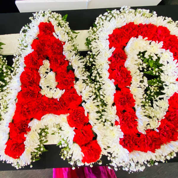 Red and white floral letters arranged on a black surface