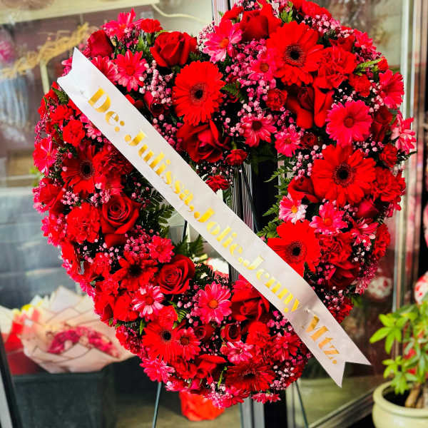 Heart-shaped red flower wreath on an easel with a name ribbon