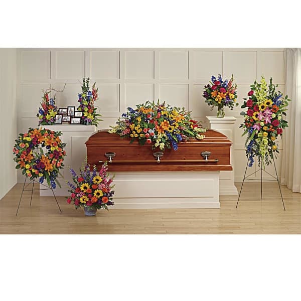 Colorful funeral casket spray with standing floral tributes