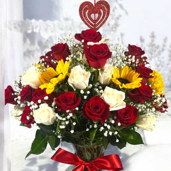 Bouquet of red and white roses with yellow sunflowers in a glass vase