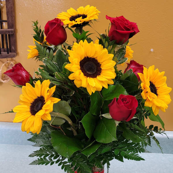 Bouquet of red roses and yellow sunflowers in a glass vase
