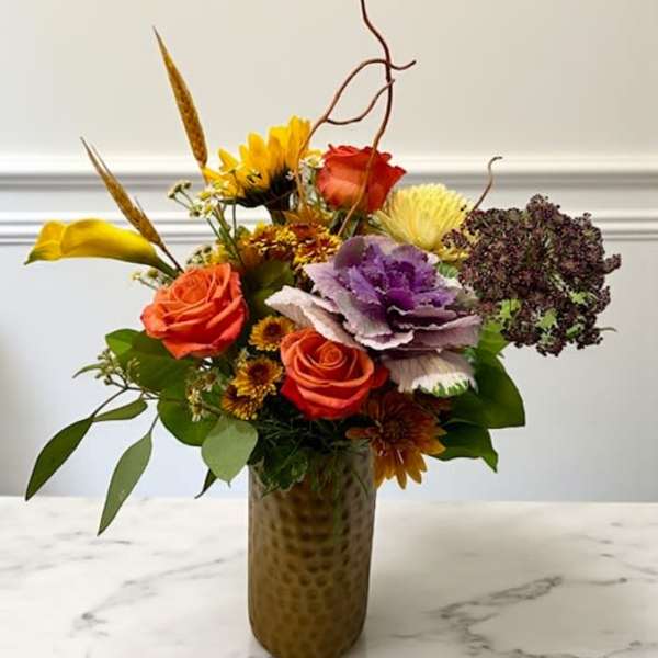 Mixed bouquet of roses, kale, and chrysanthemums in a tall vase