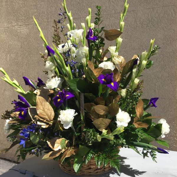 Tall floral arrangement with white and purple blooms in a wicker basket