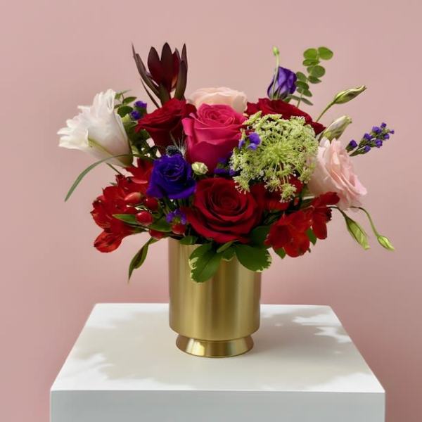 Mixed bouquet of roses and lilies in a gold vase