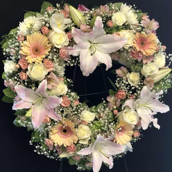Heart-shaped floral wreath with pink lilies, cream roses, and peach gerberas