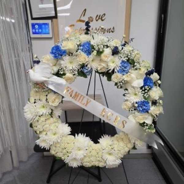 Large floral wreath with white and blue flowers on a stand