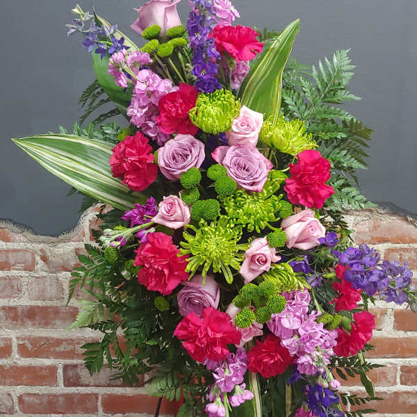 Standing floral spray with pink roses, carnations, and purple blooms