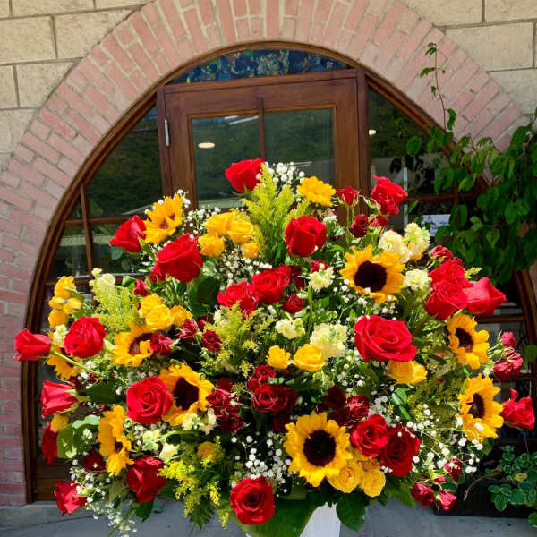 Large bouquet of red roses and yellow sunflowers in a white vase
