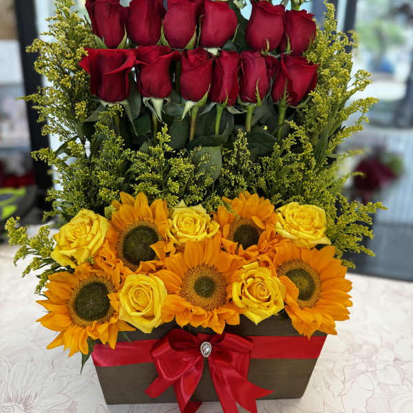 Tiered floral arrangement with red roses, yellow roses, and sunflowers in a box