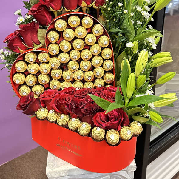 Heart-shaped box of chocolates with red roses and yellow lilies