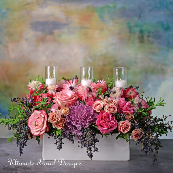 Pink and cream floral centerpiece with three glass candles in a white rectangular vase