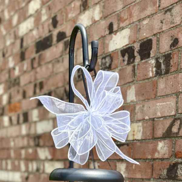 Decorative wind chime with a white bow hanging on a black metal stand