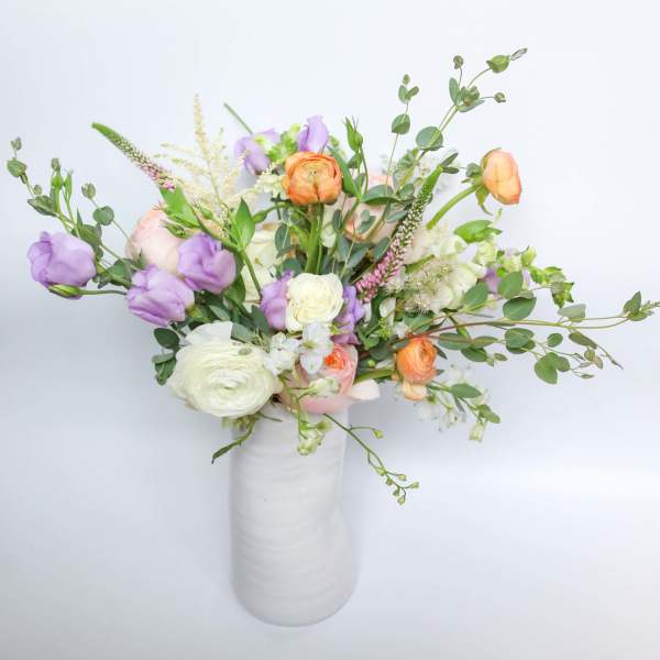 Mixed bouquet of pastel flowers in a white vase