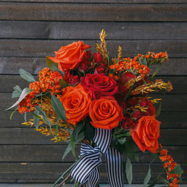 Bouquet of orange and red roses with a striped ribbon