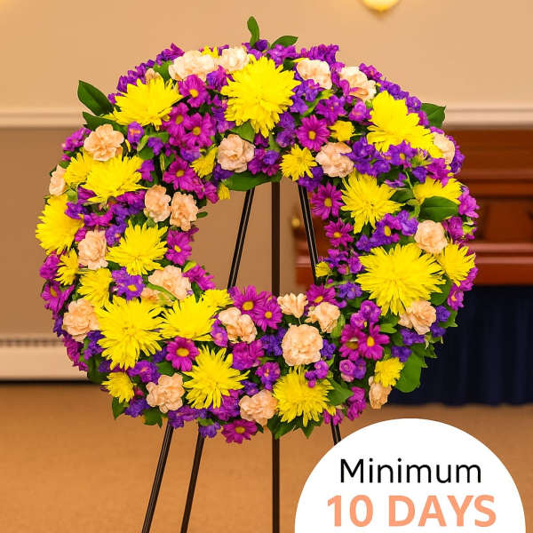 Standing wreath of yellow, purple, and peach flowers on a metal easel