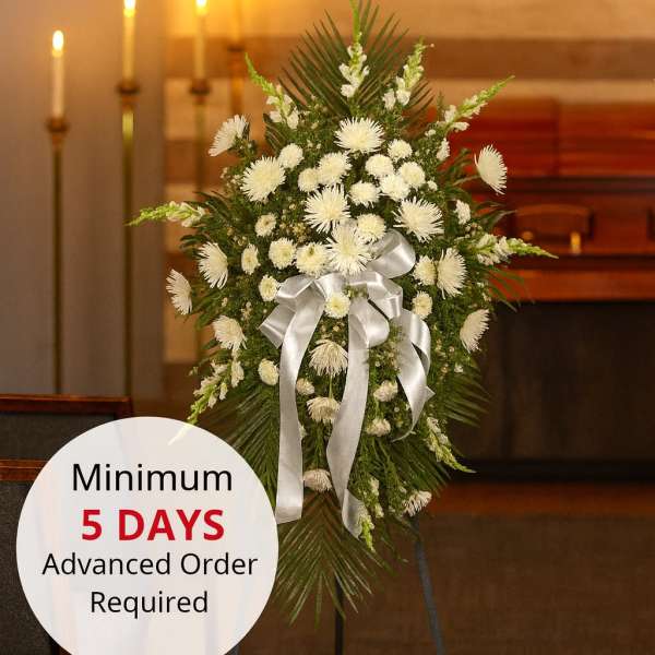 Tall white chrysanthemum standing spray with silver bow on an easel in a chapel setting