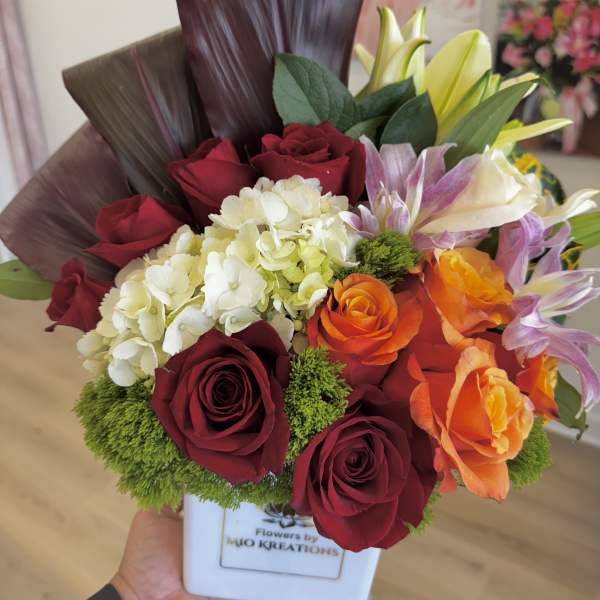Bouquet of red and orange roses with white hydrangea in a white vase
