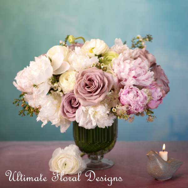 Pink and white bouquet in a green glass vase with a candle nearby