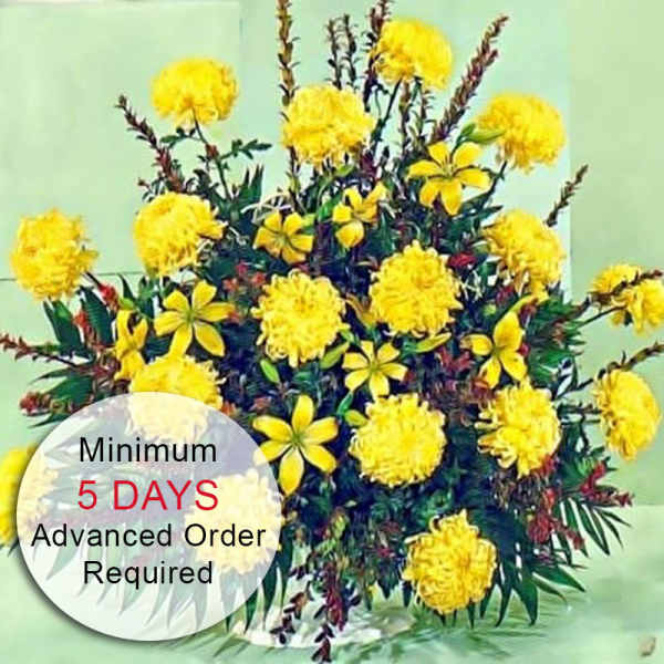Yellow marigold arrangement with smaller yellow blooms in a low white container on a pale green background