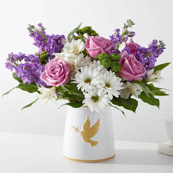 Pink roses and white daisies in a white vase with a gold dove design