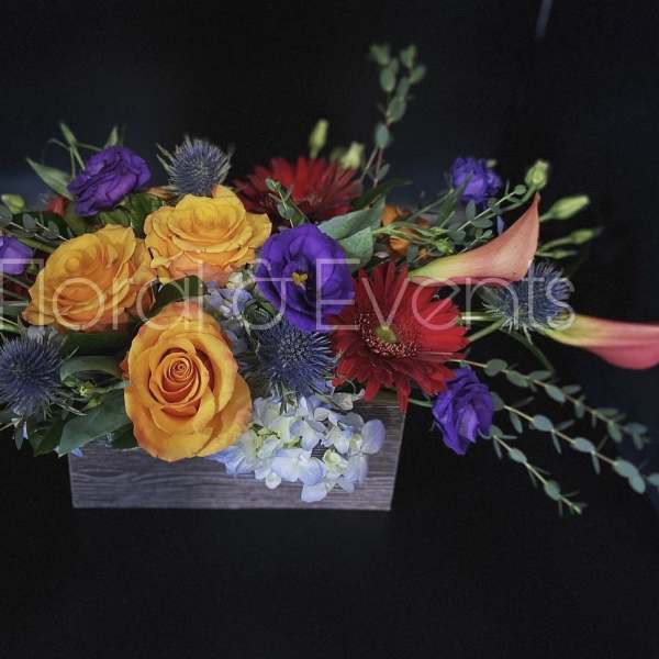 Colorful floral arrangement in a rectangular wooden box with roses and calla lilies