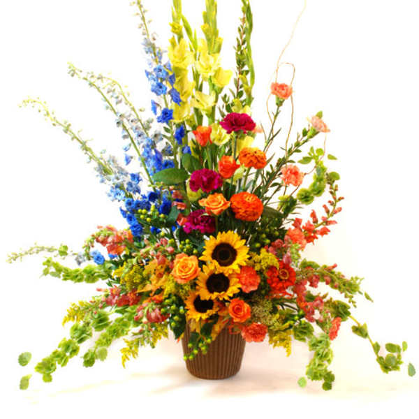 Tall mixed flower arrangement in a brown vase with sunflowers and bright blooms