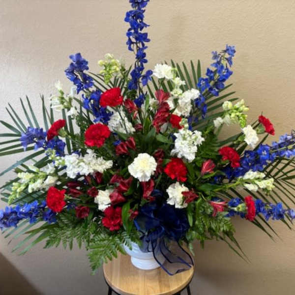 Large red, white, and blue floral arrangement in a white vase