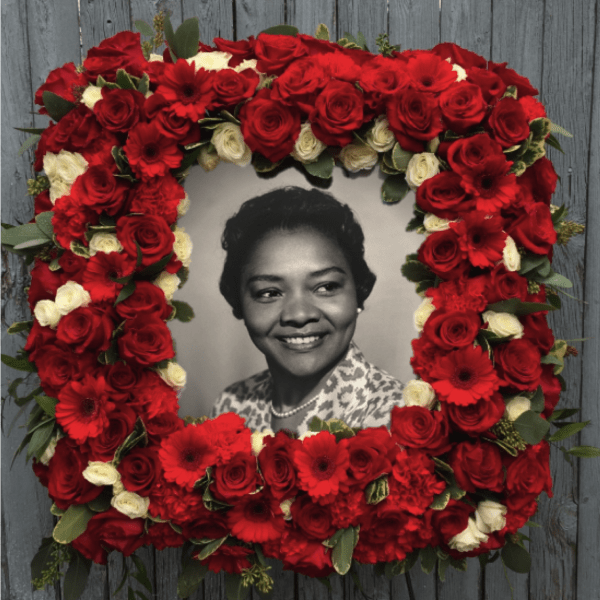 Red and white floral wreath surrounding a black-and-white portrait