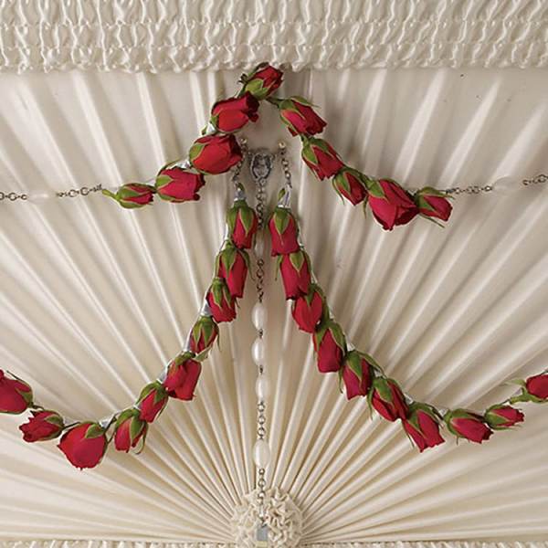 Red rose buds arranged around a hanging cross ornament