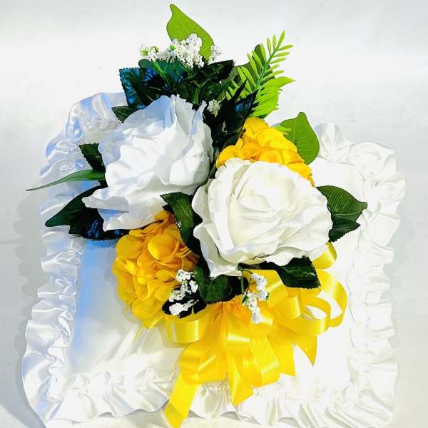 White and yellow bouquet with satin ribbon on a white ruffled cloth