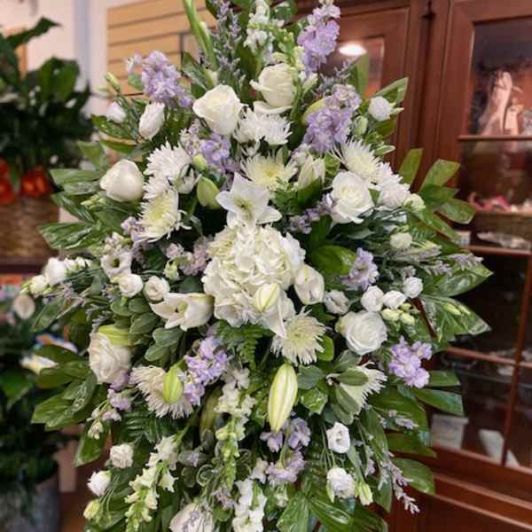 Large white and lavender funeral spray on an easel