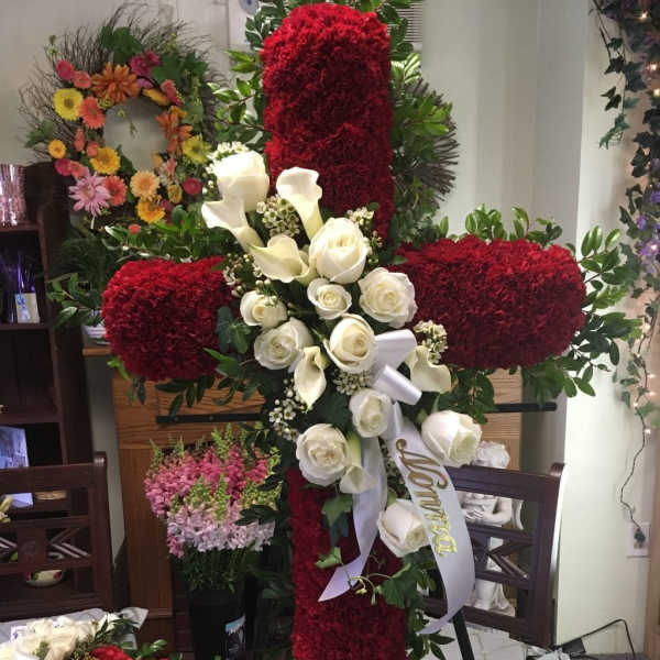 Large red floral cross with white roses and calla lilies on an easel