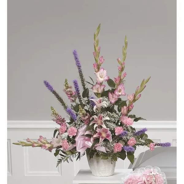 Pink and purple floral arrangement in a silver vase with a ribbon bow