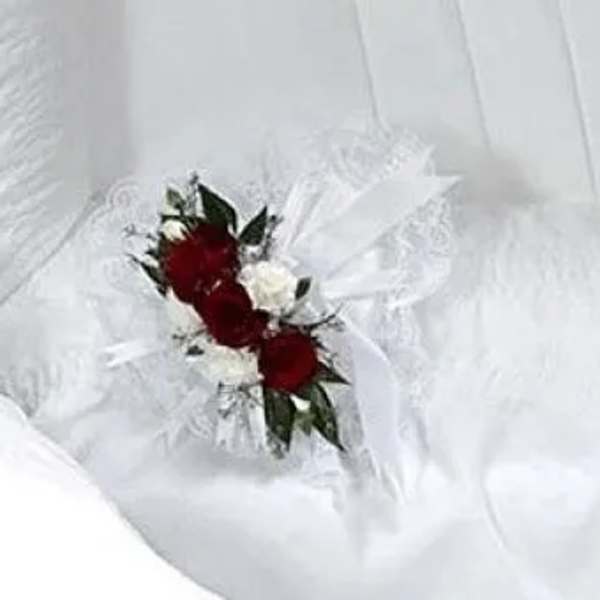 Small red and white floral corsage on white fabric