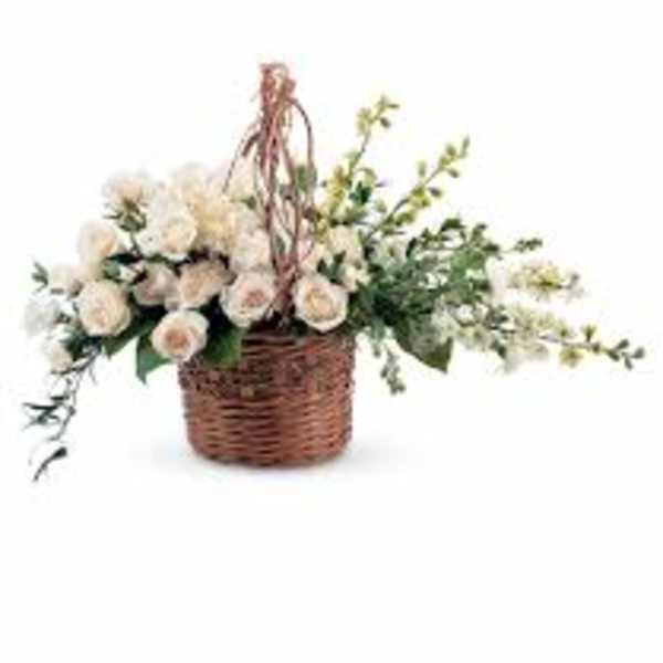 White roses in a wicker basket with trailing greenery