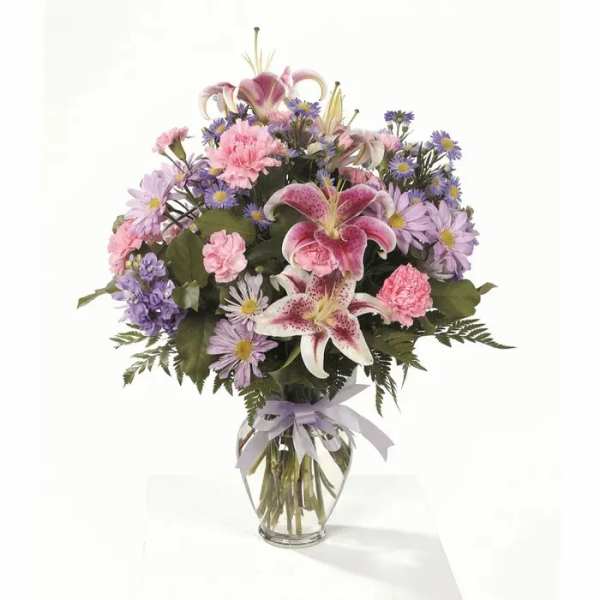 Bouquet of pink lilies, carnations, and purple daisies in a glass vase