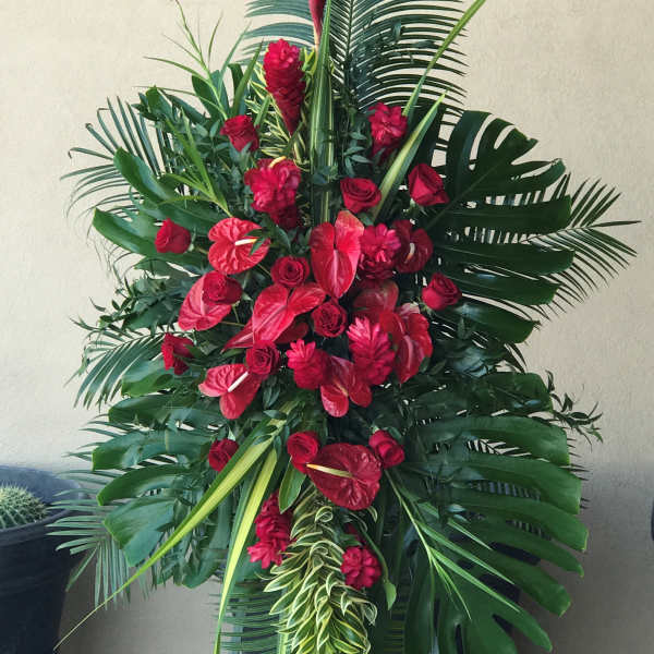 Tall red floral standing spray with tropical leaves on an easel