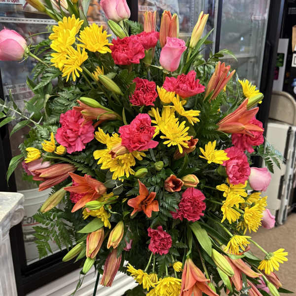 Standing floral spray with pink roses, yellow daisies, and orange lilies