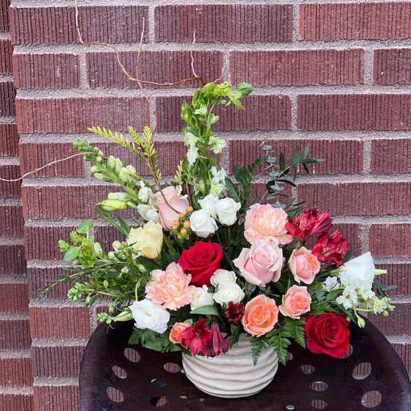 Mixed bouquet of roses, carnations, and white blooms in a white vase