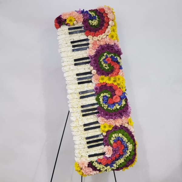 Floral arrangement shaped like a piano keyboard on a stand