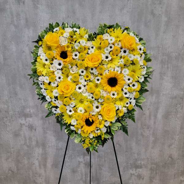 Heart-shaped yellow and white floral standing spray on an easel