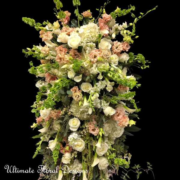 Tall floral arrangement with white roses, calla lilies, and pale pink blooms