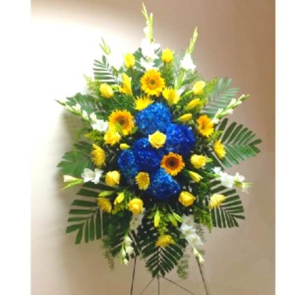 Tall standing spray with blue hydrangeas and yellow blooms on a metal easel