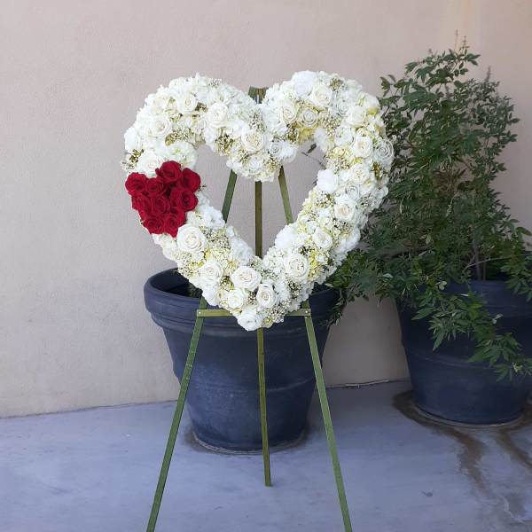 Heart-shaped white rose wreath with a red rose cluster on an easel