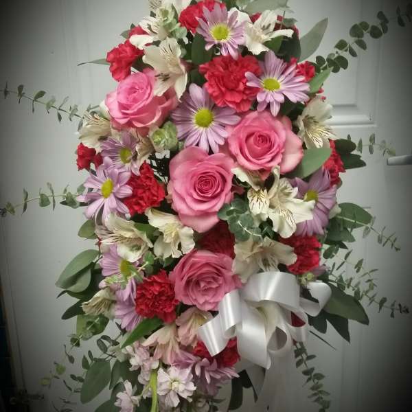 Pink and red mixed flower arrangement with a white ribbon