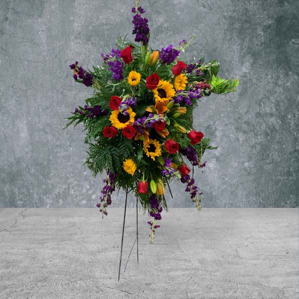 Standing floral spray with red roses, sunflowers, and purple blooms