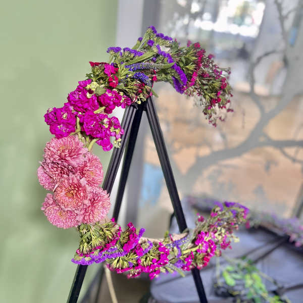 Floral wreath with pink and purple blooms on a black stand
