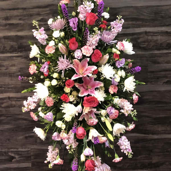 Large standing floral spray with pink lilies, red roses, and purple blooms