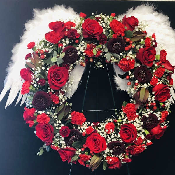 Heart-shaped floral wreath with red roses and white feathers
