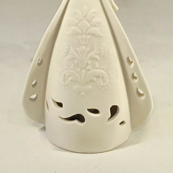 Cream ceramic angel figurine with cutout details and an embossed pattern on the gown.